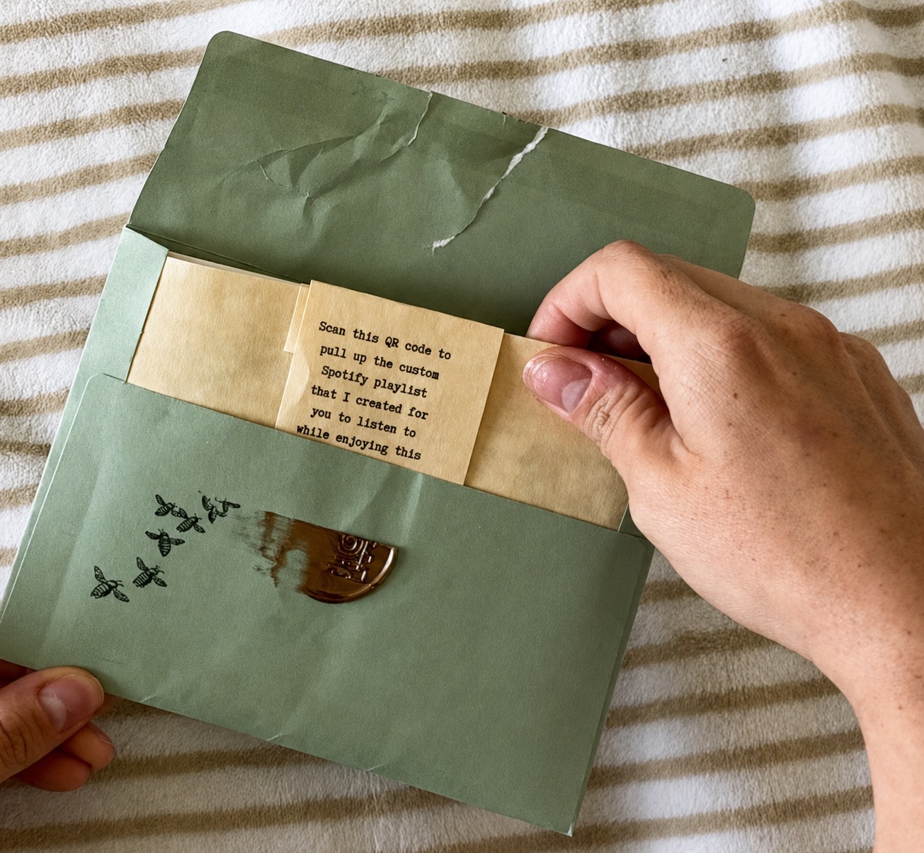 A hand lifting the contents out of a wax-sealed green envelope — snail mail letter subscription — Moss & Mail