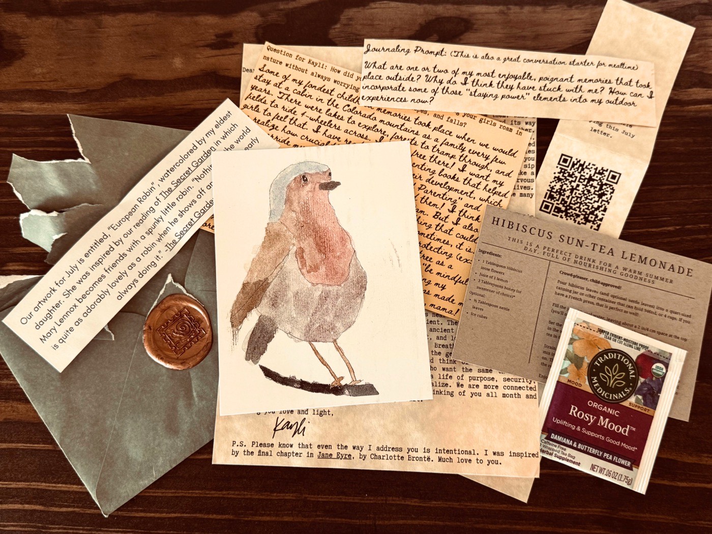 The full spread of one month's Moss & Mail envelope — letter, tea, watercolour art, journaling prompt and recipe card — Moss & Mail